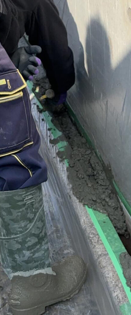 作業員が基礎部分にコンクリートを打設している様子