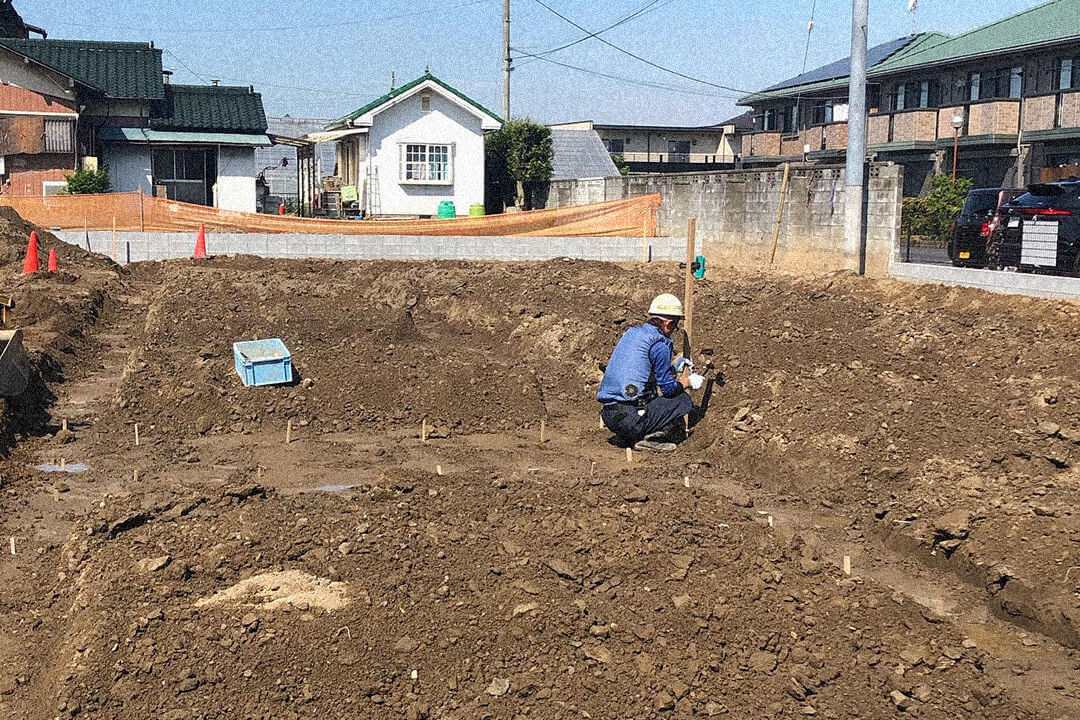 住宅建設現場で測量作業を行う作業員。