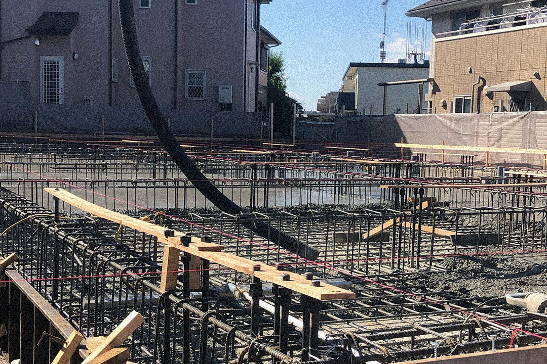 鉄筋を組み終えた基礎にコンクリートを流し込み、固めている建設現場