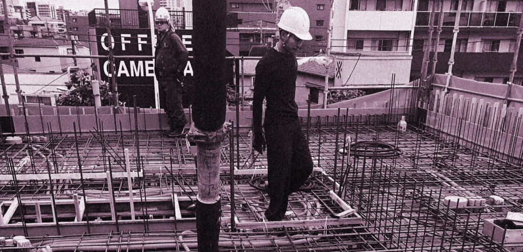 鉄筋を組んだ建設現場で作業を行うヘルメット姿の作業員