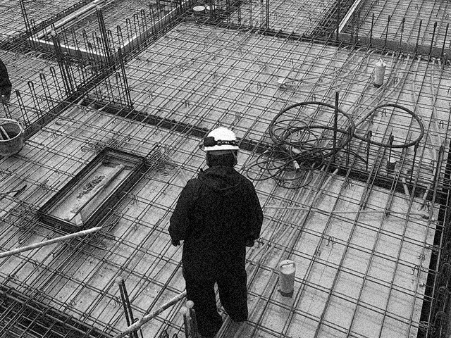 鉄筋を組んだ基礎工事現場で確認作業をする作業員