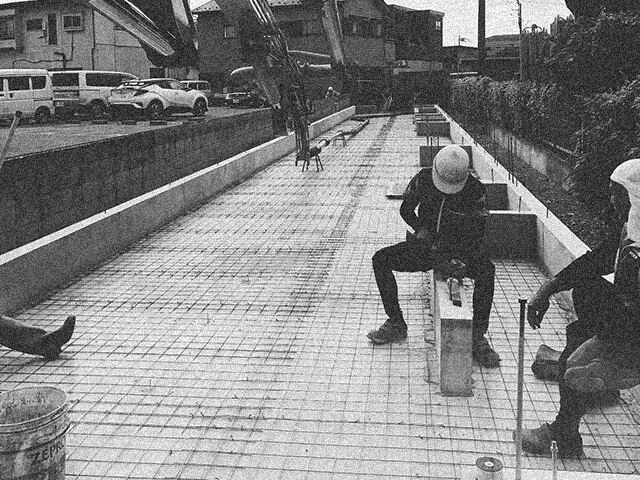 鉄筋を組んだ現場で休憩をとる作業員たち