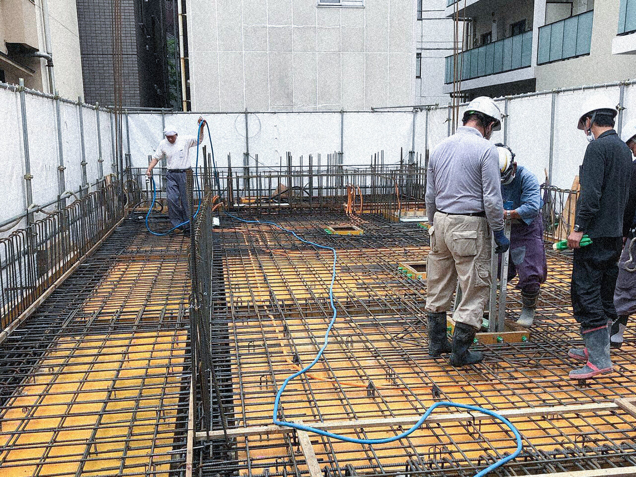 鉄筋が組まれた基礎工事現場で作業を進める建設作業員たち